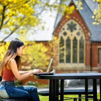 Student working in front of Sage Chapel