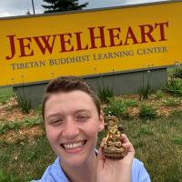 Emma Plowe smiling in front of the Jewel Heart entrance sign